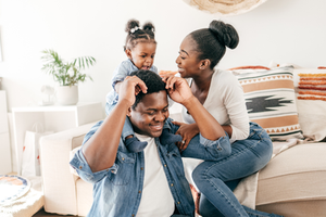 Couple by couch laughing and playing with their baby girl