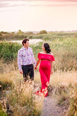 Pregnant woman walking with partner long grass golden hour