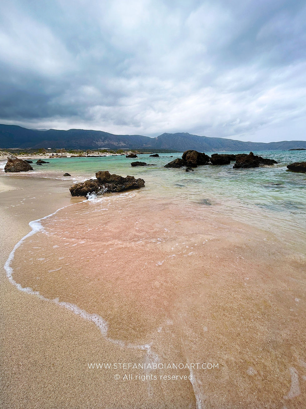 Elafonisi Beach in Crete, a beach with pink sanl cleard, crystal green water , rocks in the sea and a cloudy sky