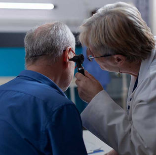 Otorrinolaringólogo examinando el oído de un hombre mayor