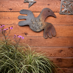 Metal bird ornament on a wood fence in a DC garden