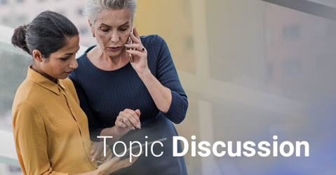 Two businesswomen discussing, one on phone, with 