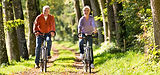 Older couple riding bikes on a sunny trail