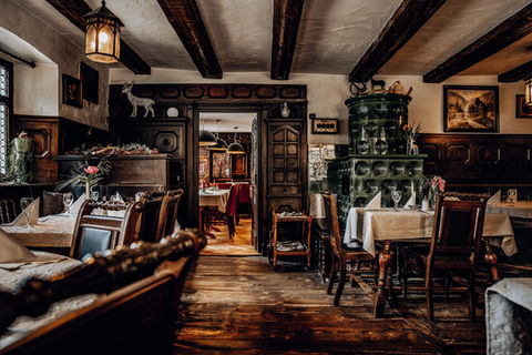 Gemütliches, rustikales Restaurant mit Holzbalken, Kachelofen und Holztischen.