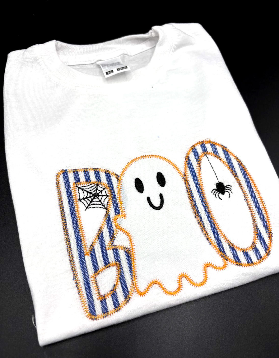 Angled view of Boo Ghost T Shirt, with blue striped fabric and embroidered spider and spiders web