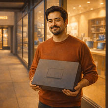 Javier standing outside a computer shop with his new laptop.