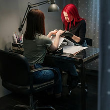 A red haired nail technician doing a client's nails in her office. ESL lesson on service j