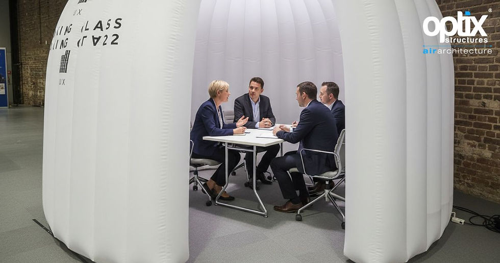 Four-person meeting inside a 3 × 3m Optix Inflatable Office Pod showing the compact boardroom layout.