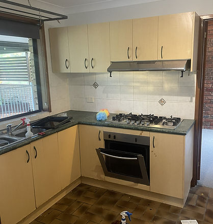 Original kitchen with cream overhead and base cabinets, dark benchtops, tiled splashback, gas cooktop and built-in oven.