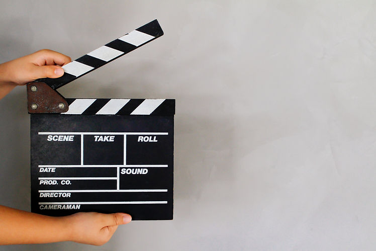 Kid's hand holding film clapper board with gray concrete loft style wall background textur