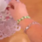 Bracelet blanc petites fleurs en perles en acrylique porté sur une main qui prend une tasse