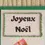 Miniature : Gros plan texte joyeux noel tracé à la plume et encadré de perles cousues sur carte cadeau dans cheminée