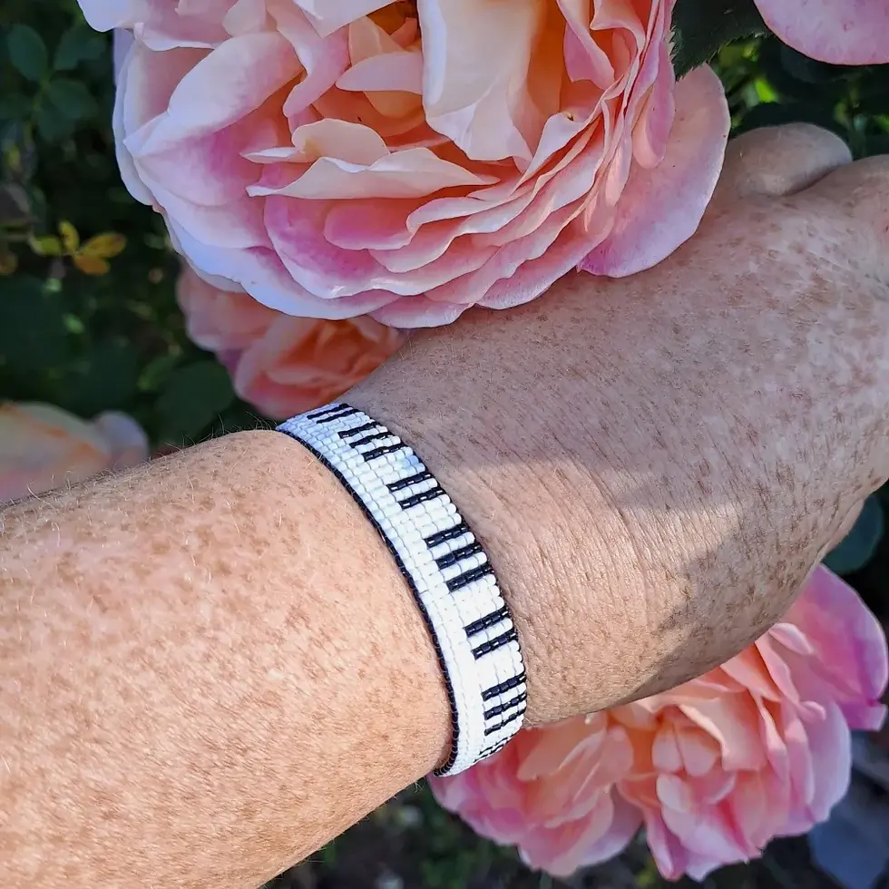 Miniature : bracelet motif piano en perles de rocaille miyuki tissées, porté, main qui ramasse des roses
