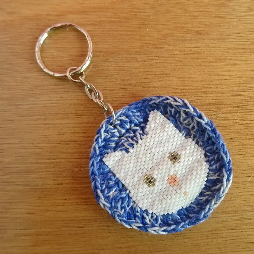 Miniature : gros plan porte clé tête de chat blanc en perles de rocaille tissées sur rond au crochet bleu