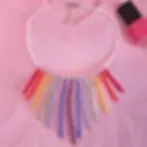 Collier arc en ciel en perles en cristal posé sur un t shirt rose avec un flacon de vernis