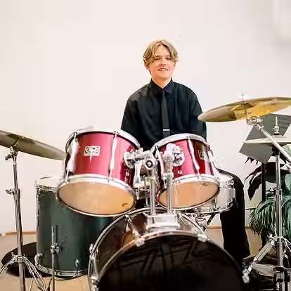 older student smiling with drums