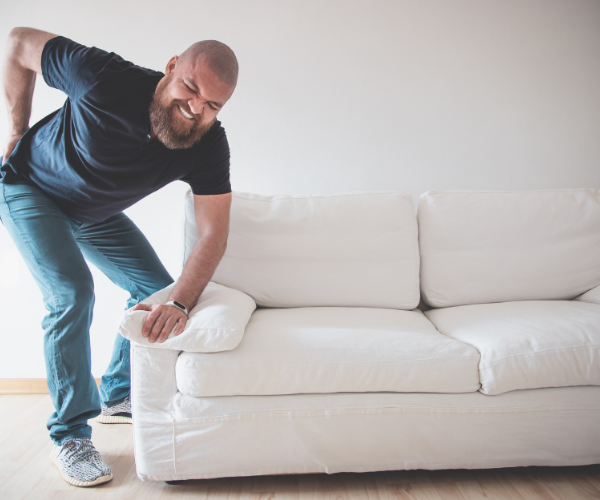 Man picking up a couch with back pain.