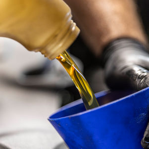Close-up of fresh golden engine oil being poured through a funnel during an oil change at Precision Auto Repair in West Springfield