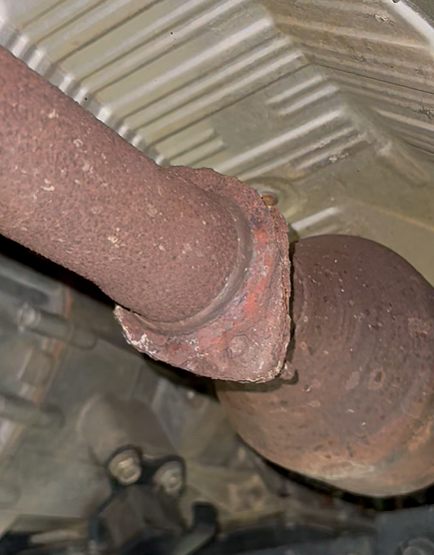Corroded exhaust pipe connection with heavy rust damage found during routine maintenance inspection