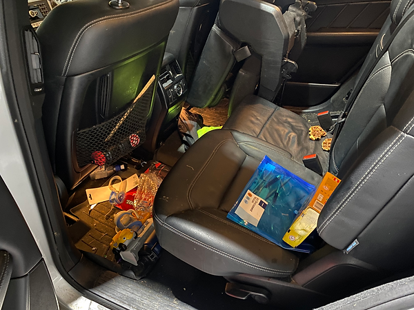 Dirty family car interior with children's food, drink boxes and crumbs on the floor