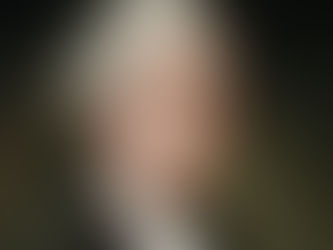 A portrait of an older man with white hair, wearing a dark coat and white cravat, set against a dark, muted background. He looks serious.