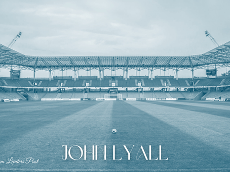 Empty stadium with a football on the field. Blue tone. Text: "Lessons From Leaders Past" and "John Lyall." Quiet atmosphere.