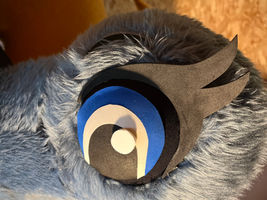 Close-up of a professionally restored mascot eye with layered foam details and soft faux fur, photographed under warm lighting.