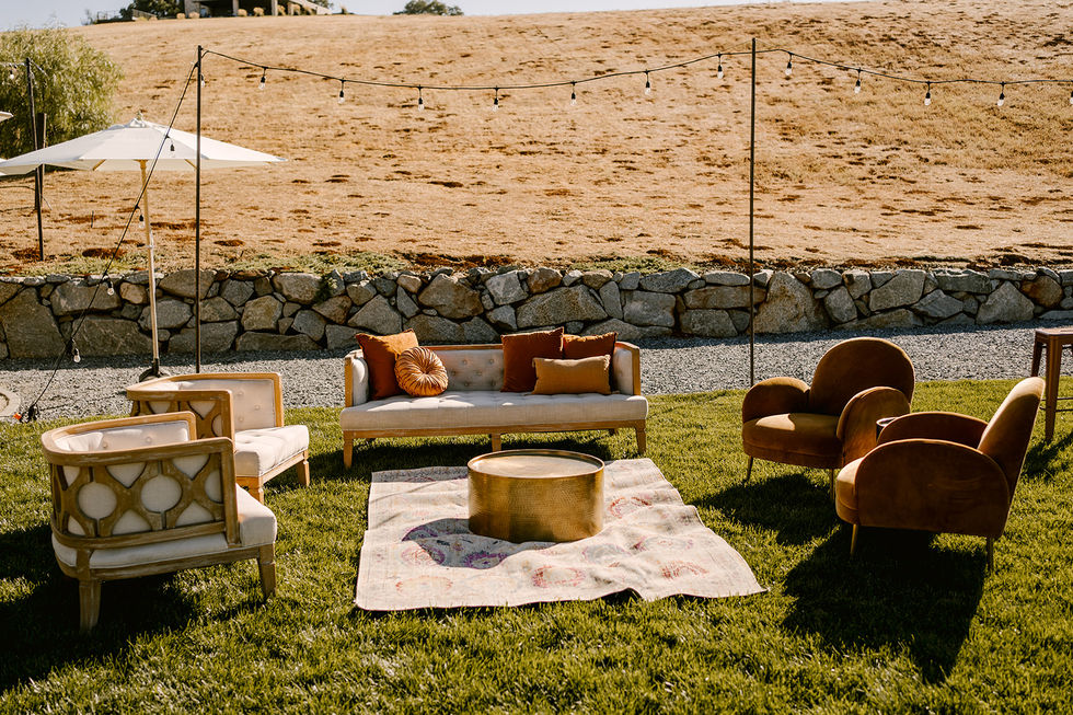 a couch and chairs are sitting on a rug in the grass