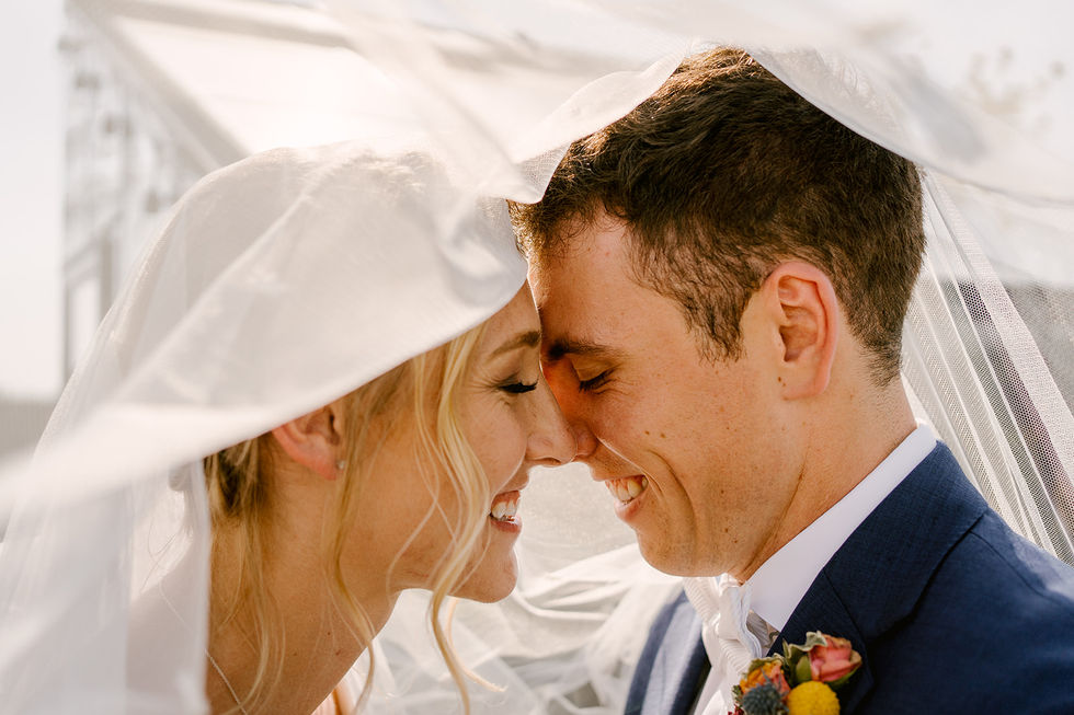 a bride and groom kissing under a white veil