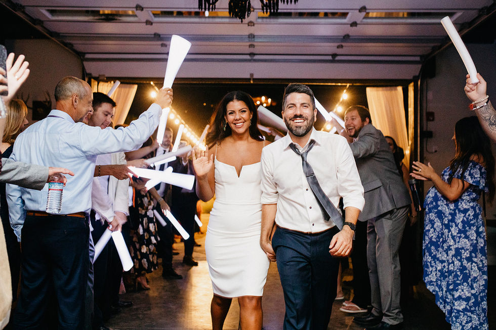 a bride and groom are walking through a crowd of people holding light sticks