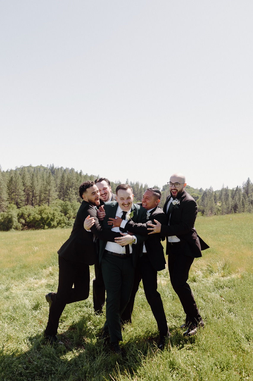a group of men in suits hugging each other in a field