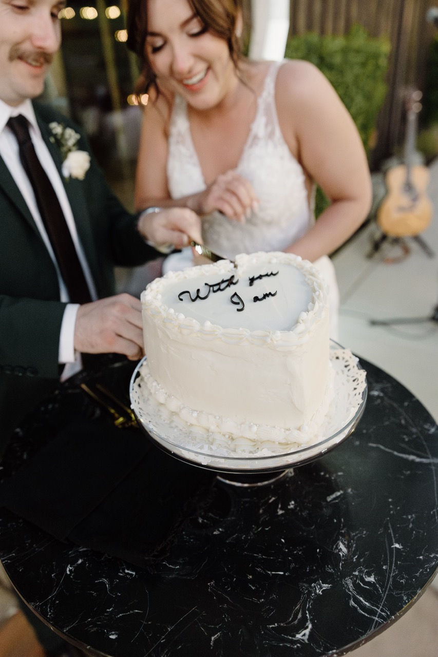 a bride and groom are cutting a heart shaped cake that says " will you g am "