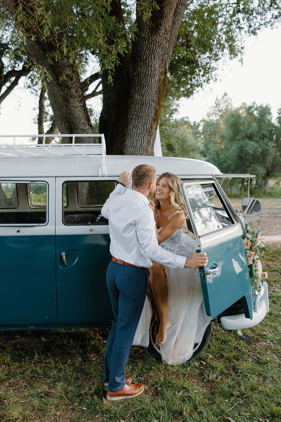 a bride and groom kissing in front of a blue van