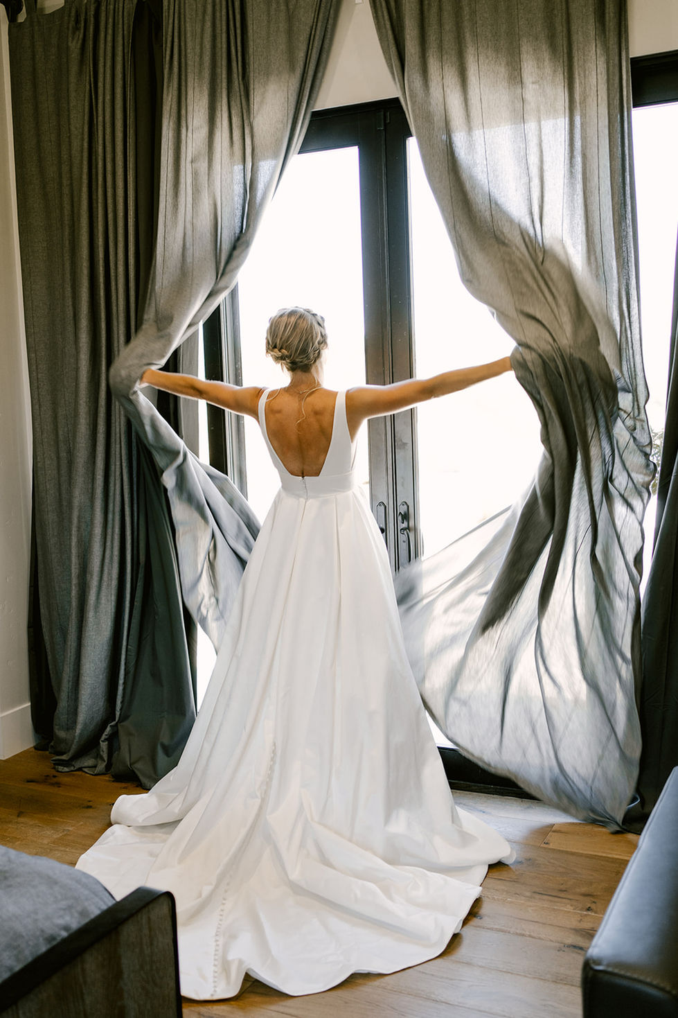 a woman in a white dress is standing in front of a window with her arms outstretched