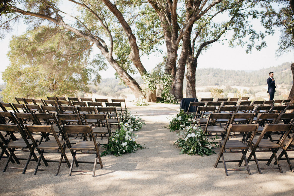 a row of wooden folding chairs are set up for a wedding ceremony