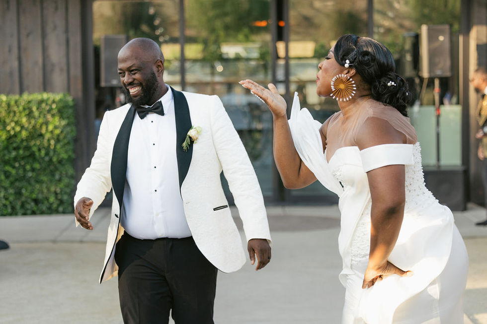 a man in a tuxedo and a woman in a white dress blowing a kiss