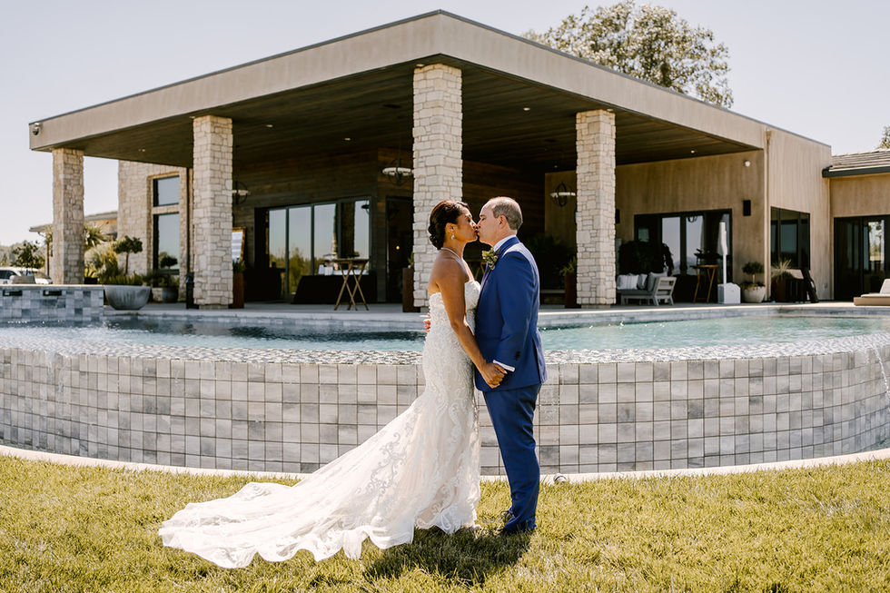 a bride and groom kissing in front of a house