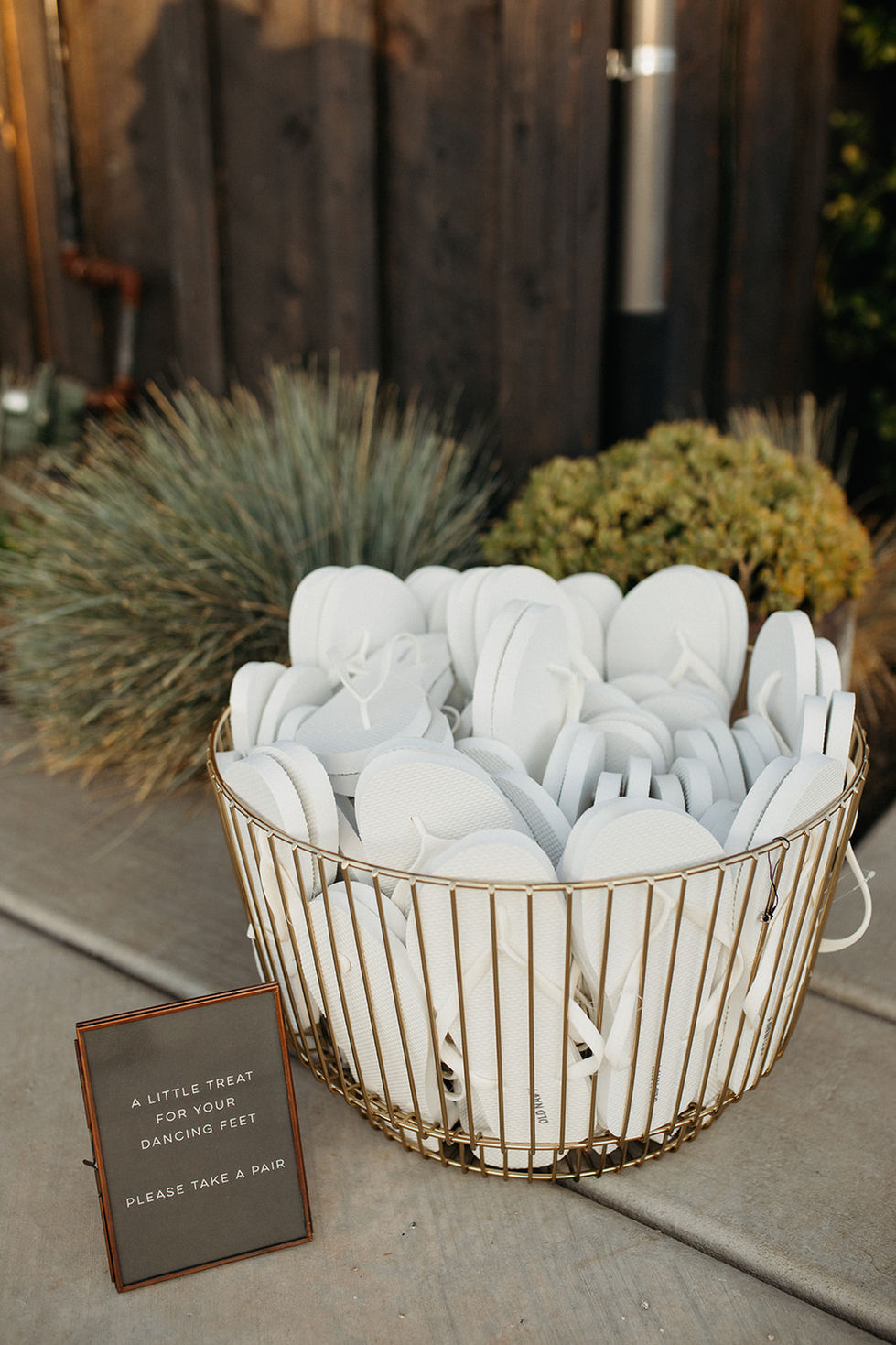 a basket of flip flops with a sign that says a little treat for your guest