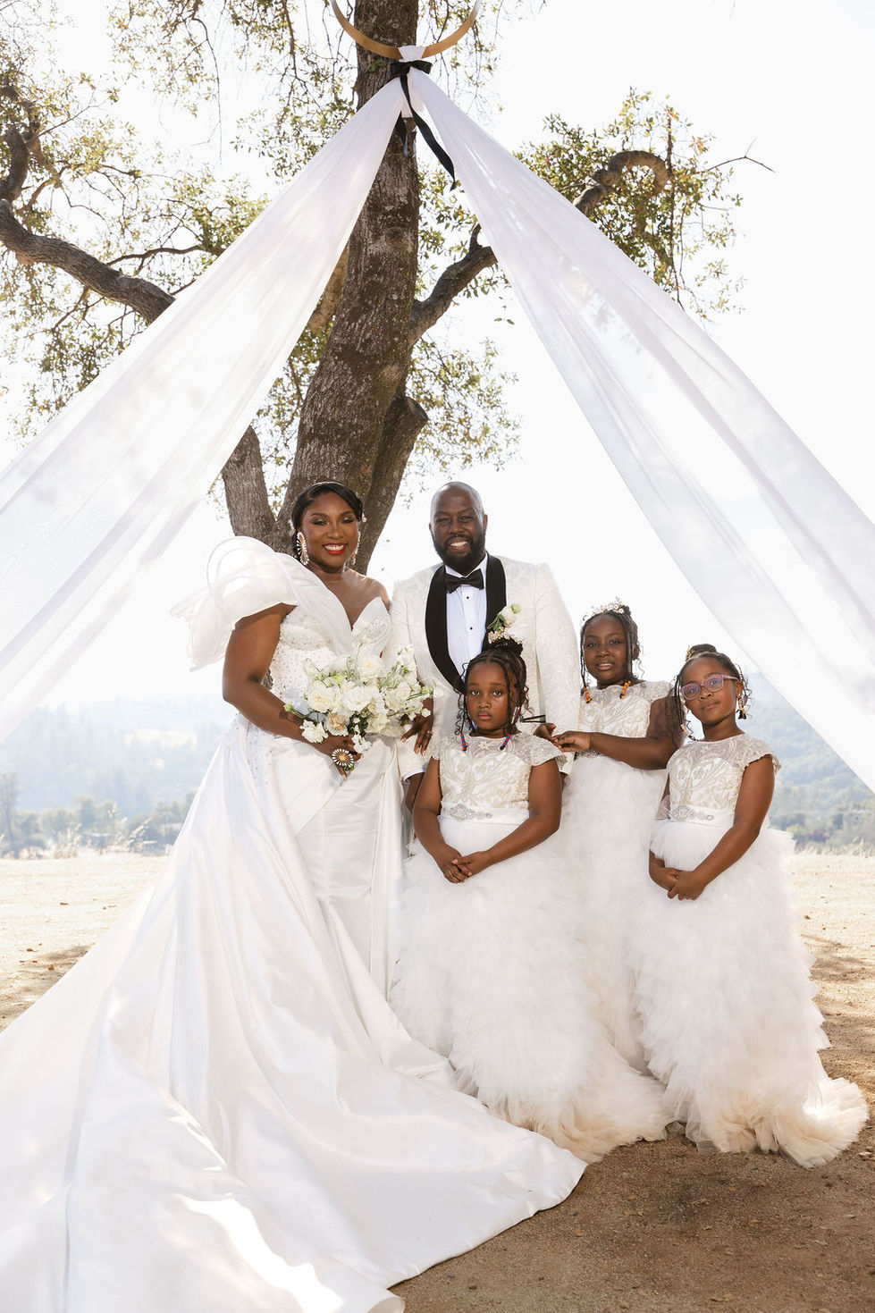a bride and groom pose with their flower girls