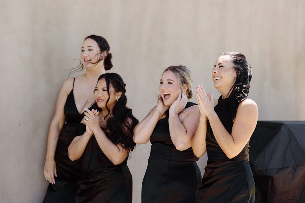 four women in black dresses are clapping and laughing