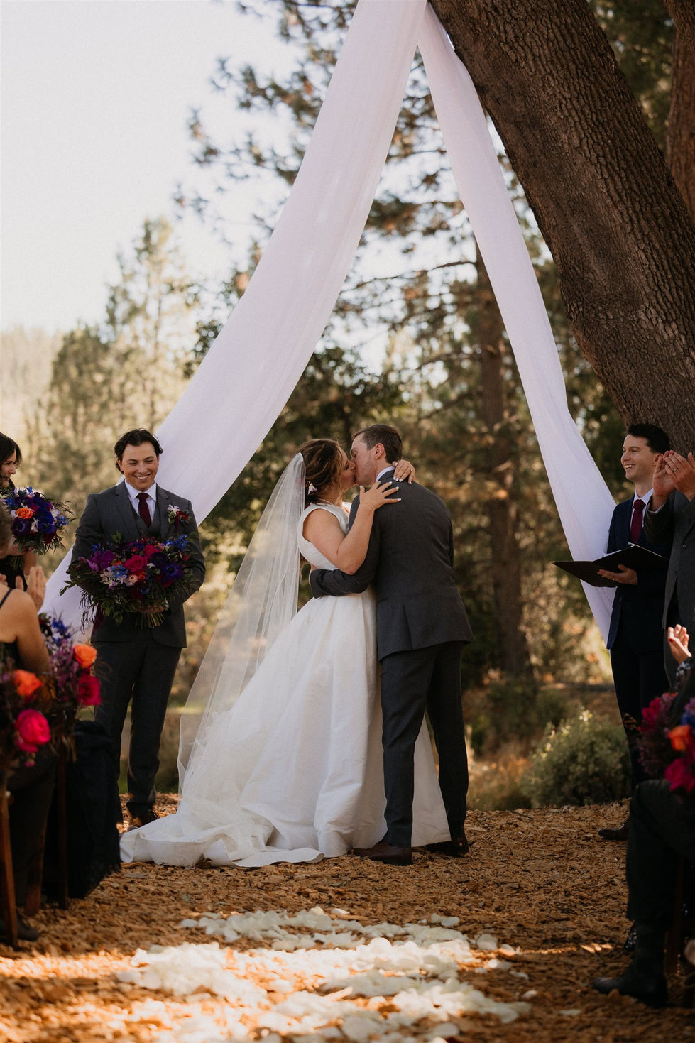 a bride and groom kiss during their wedding ceremony