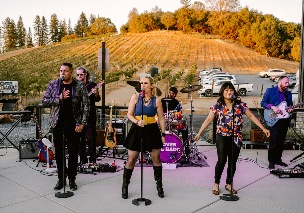 a group of people singing in front of a purple drum that says over the bad