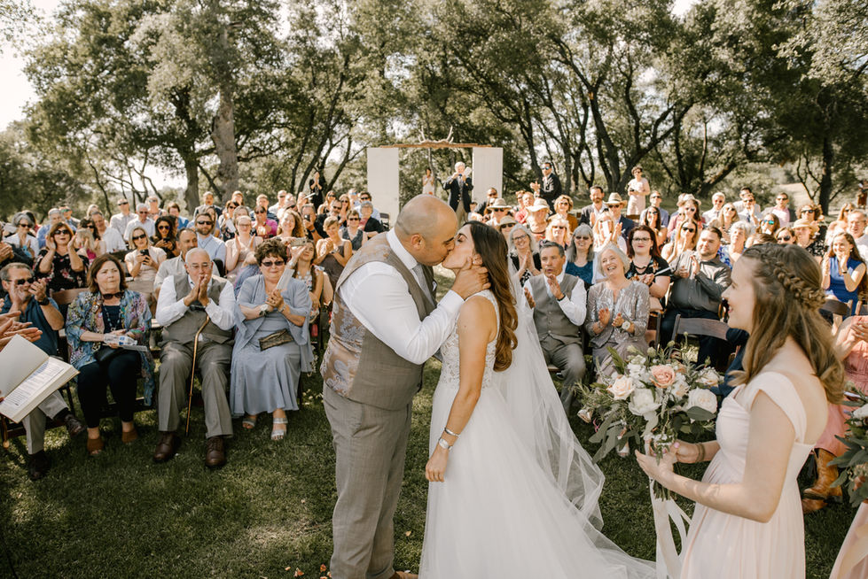 a bride and groom kiss in front of their wedding guests