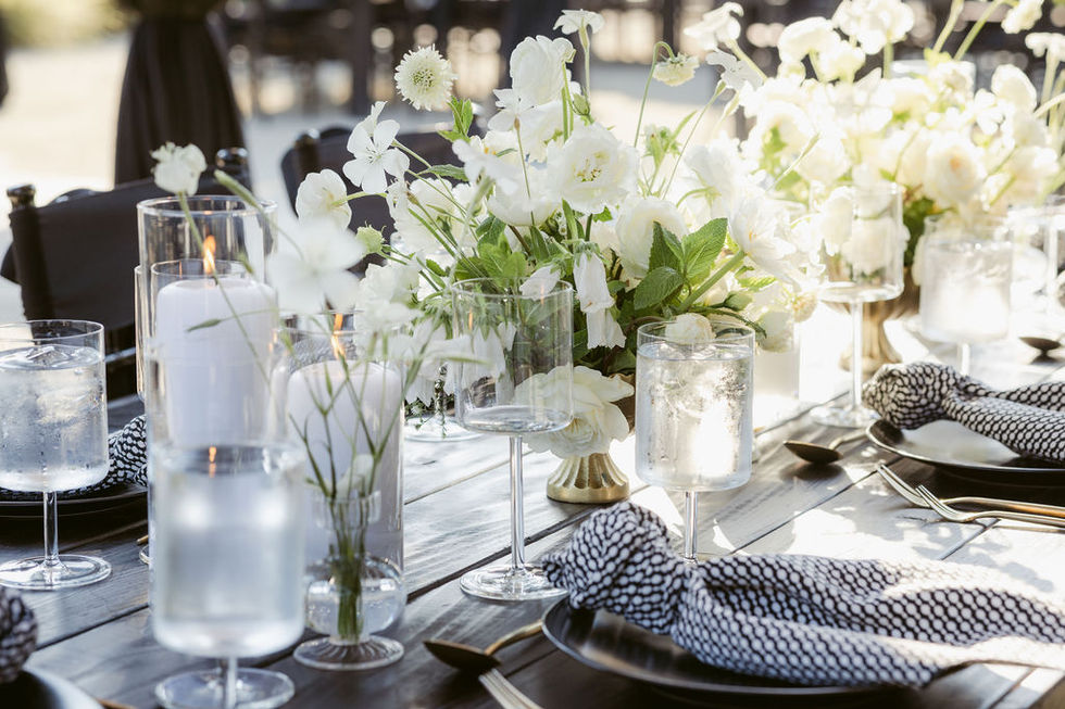 a table setting with white flowers and wine glasses