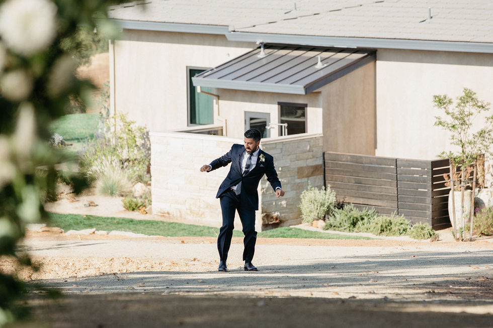 a man in a suit is dancing in front of a house