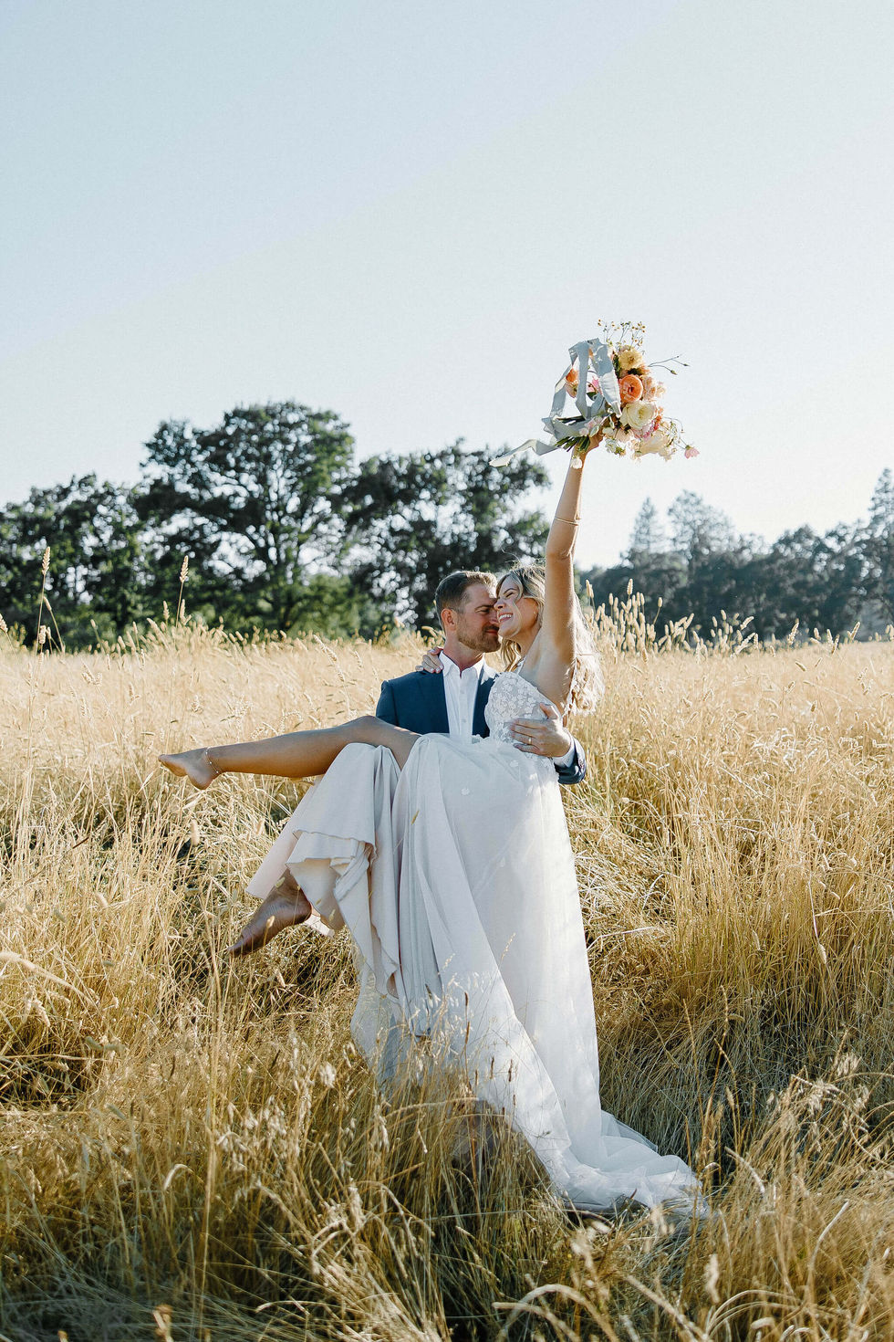 a bride and groom are kissing in a field of tall grass