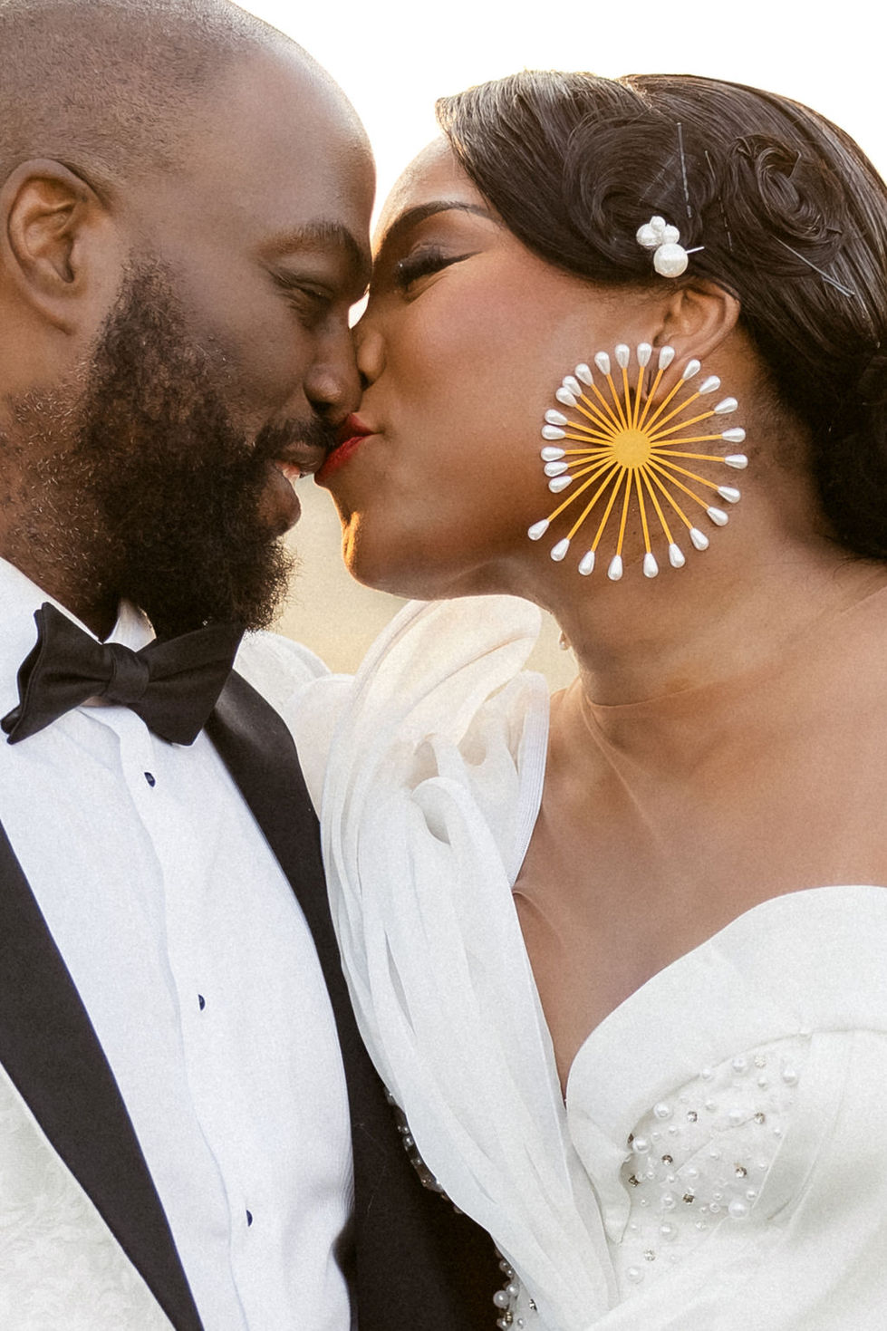 a bride and groom kissing with the bride wearing large earrings