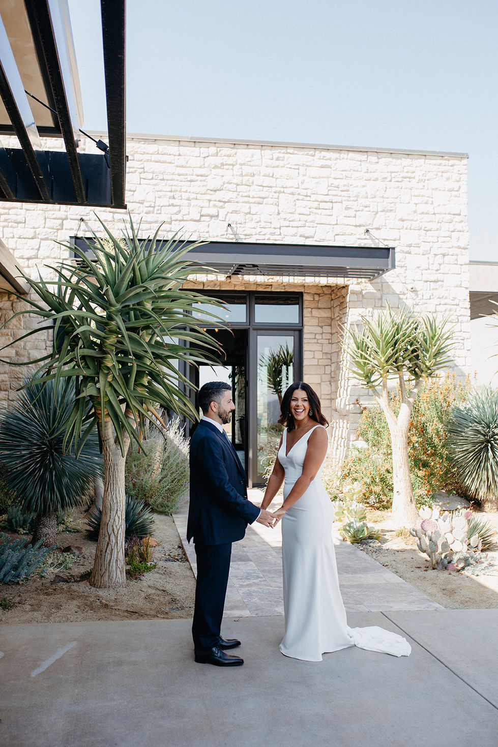 a bride and groom hold hands in front of a stone building