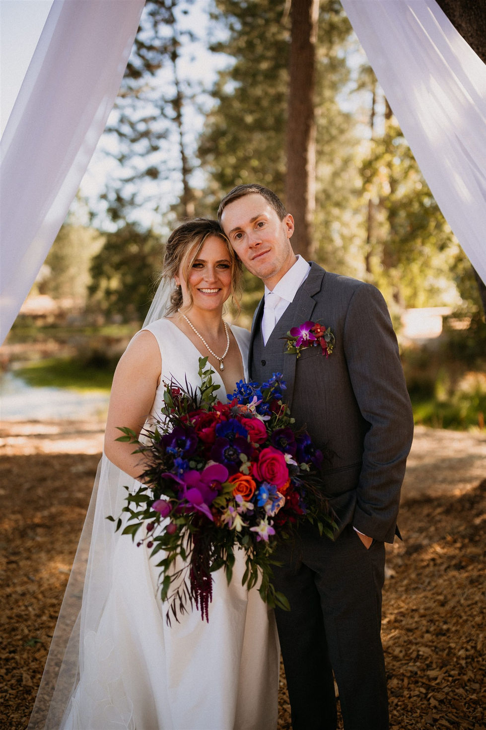 a bride and groom pose for a picture with a bouquet of flowers