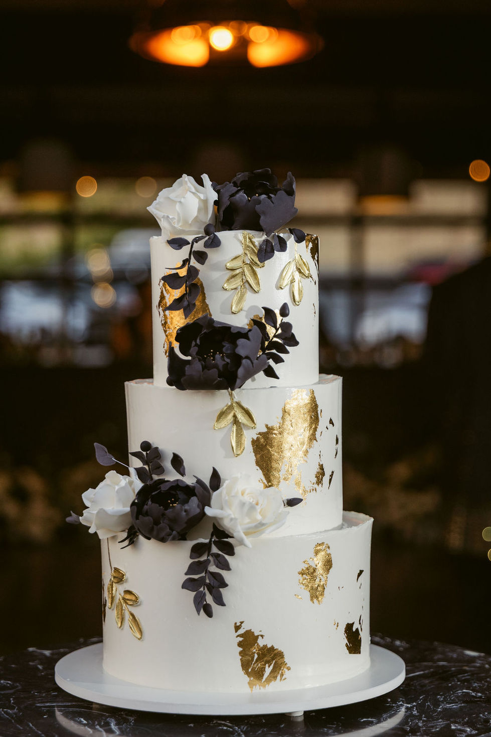 a white cake with black and gold flowers and leaves